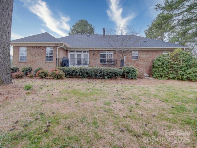 back of property featuring brick siding and a yard