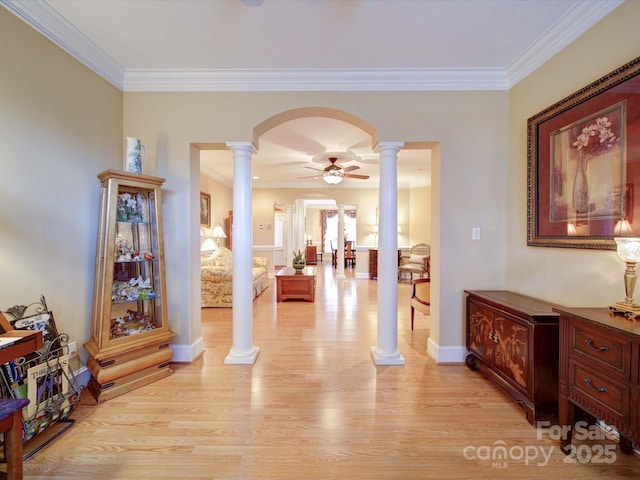 corridor featuring crown molding, baseboards, light wood-style floors, arched walkways, and ornate columns