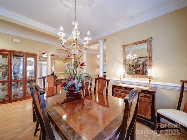 dining space with crown molding, a chandelier, light wood-type flooring, decorative columns, and arched walkways