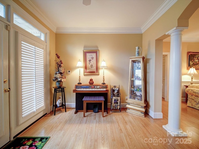 living area with decorative columns, wood finished floors, and crown molding