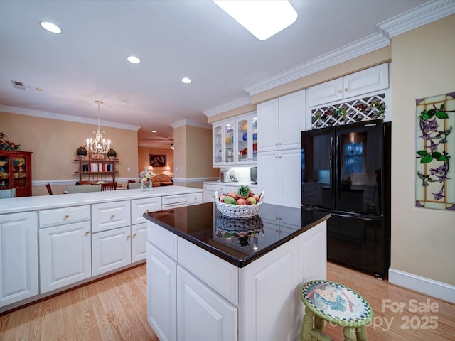 kitchen with a center island, glass insert cabinets, light wood-type flooring, ornamental molding, and freestanding refrigerator