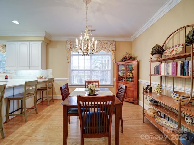 dining room with crown molding, a notable chandelier, baseboards, and light wood finished floors