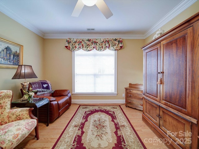 living area with visible vents, baseboards, ceiling fan, ornamental molding, and light wood-style flooring