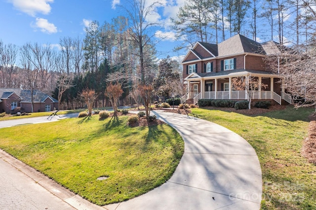 view of front of property featuring driveway, covered porch, a front yard, and brick siding