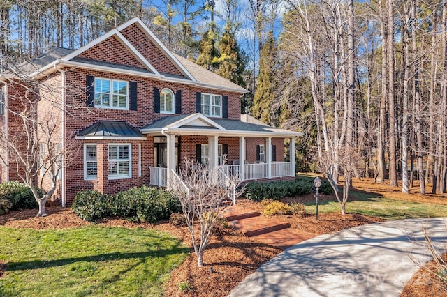 view of front of property with a porch, roof with shingles, a front yard, and brick siding