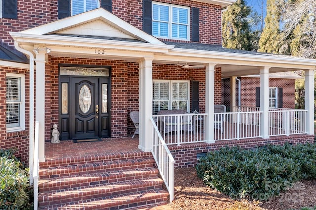 view of exterior entry featuring covered porch and brick siding