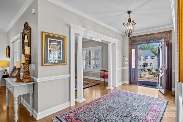 foyer featuring ornate columns, baseboards, crown molding, and wood finished floors