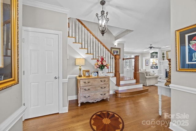 foyer featuring ceiling fan, stairway, a fireplace, and wood finished floors