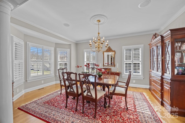 dining room featuring light wood finished floors, baseboards, visible vents, crown molding, and a chandelier