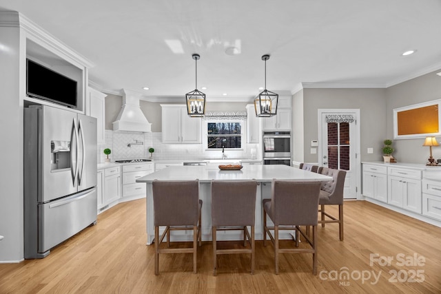 kitchen with custom range hood, appliances with stainless steel finishes, light countertops, light wood-style floors, and white cabinetry