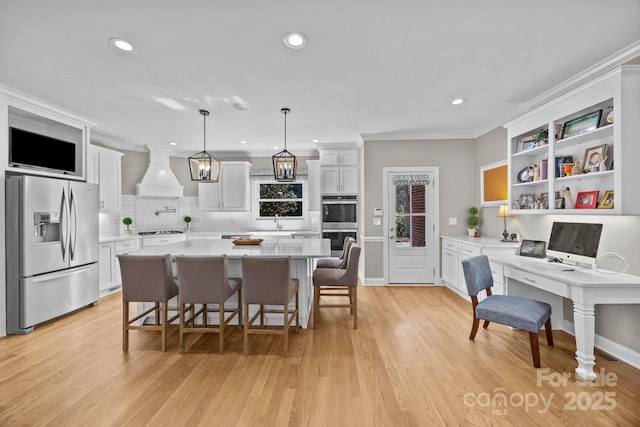 kitchen with premium range hood, a sink, white cabinets, light countertops, and appliances with stainless steel finishes