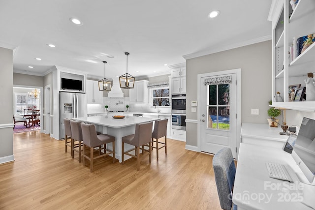 kitchen featuring stainless steel appliances, light countertops, a chandelier, light wood-type flooring, and a kitchen bar