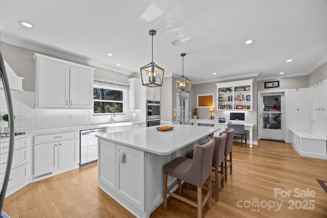 kitchen with white cabinets, a kitchen island, stainless steel appliances, and light countertops