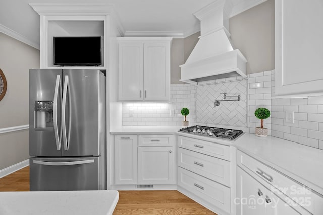 kitchen featuring custom range hood, stainless steel appliances, crown molding, and light countertops