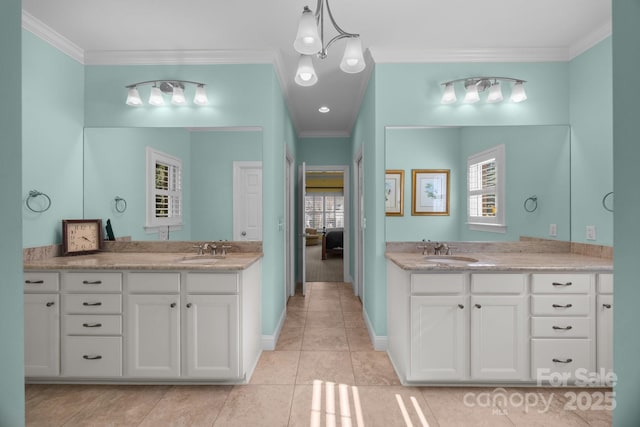 ensuite bathroom with crown molding, two vanities, and a sink