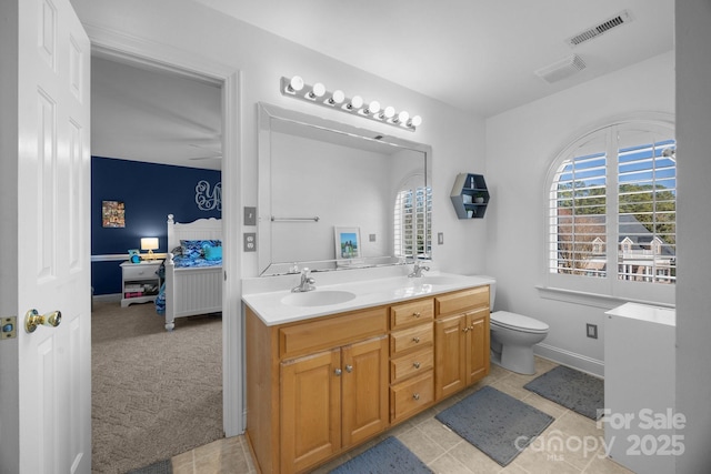 ensuite bathroom featuring ensuite bathroom, toilet, a sink, visible vents, and double vanity