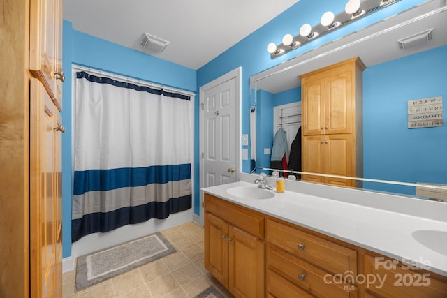 full bath with double vanity, a shower with shower curtain, a sink, and visible vents