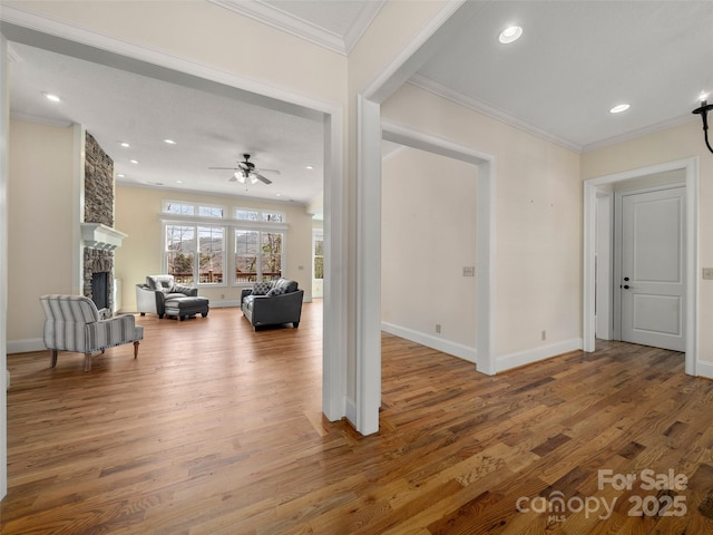 interior space featuring baseboards, ornamental molding, wood finished floors, a fireplace, and recessed lighting