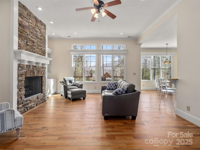 living area with baseboards, light wood finished floors, a fireplace, and crown molding