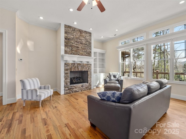 living room featuring built in features, a fireplace, crown molding, wood finished floors, and baseboards