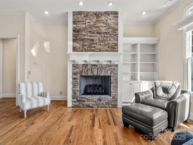 living area featuring a stone fireplace, ornamental molding, wood finished floors, and baseboards