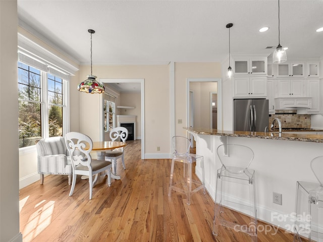 kitchen with light wood-style floors, freestanding refrigerator, glass insert cabinets, and backsplash