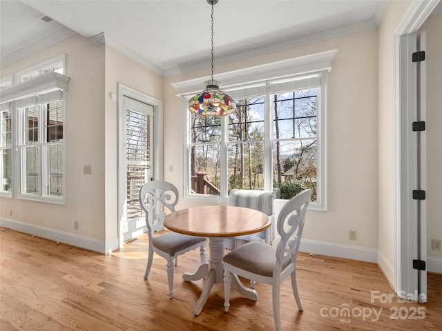 dining area with a healthy amount of sunlight, light wood-style floors, and crown molding