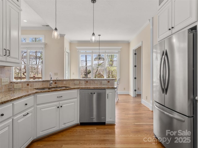 kitchen featuring crown molding, stainless steel appliances, decorative backsplash, a sink, and a peninsula