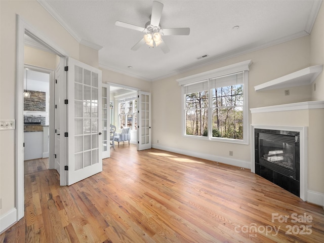 unfurnished living room featuring crown molding, french doors, visible vents, and light wood-style floors