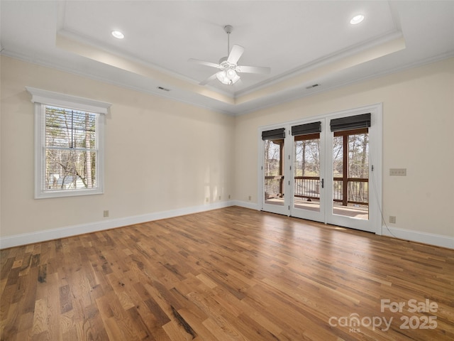 spare room with ornamental molding, wood finished floors, and a raised ceiling