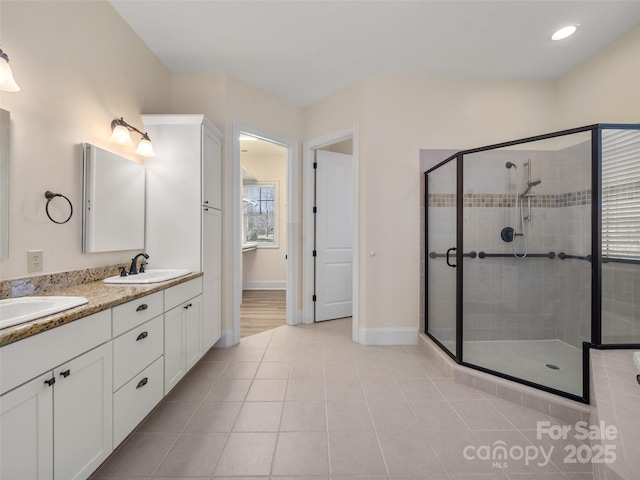 bathroom featuring tile patterned flooring, a sink, baseboards, a shower stall, and double vanity