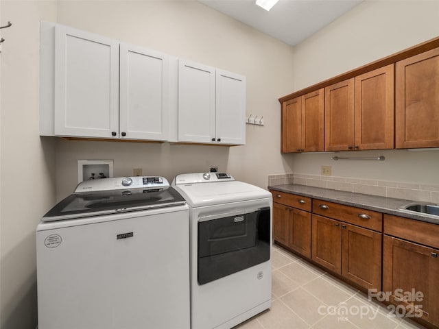 laundry room with cabinet space, washing machine and dryer, light tile patterned floors, and a sink