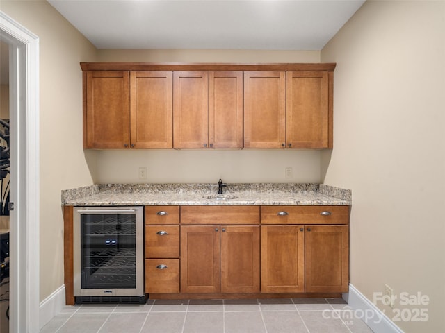 bar with beverage cooler, a sink, baseboards, and light tile patterned floors