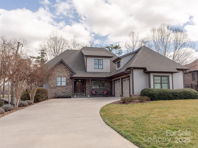 view of front facade featuring a garage, driveway, stone siding, roof with shingles, and a front yard