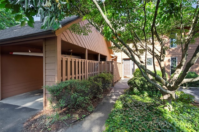 view of side of home with driveway and a shingled roof