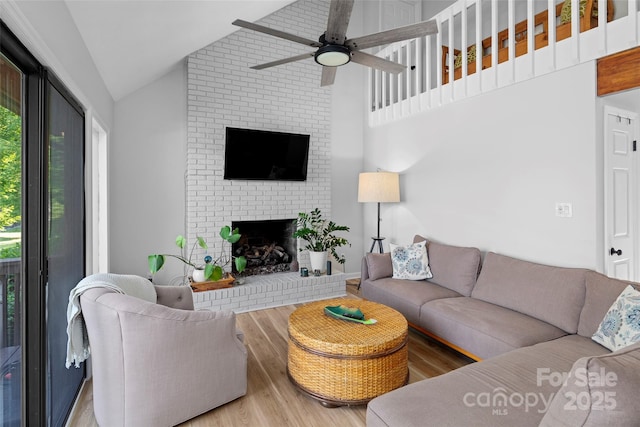 living room featuring ceiling fan, a fireplace, lofted ceiling, and wood finished floors