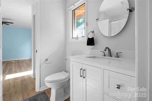 full bathroom with ceiling fan, baseboards, toilet, wood finished floors, and vanity