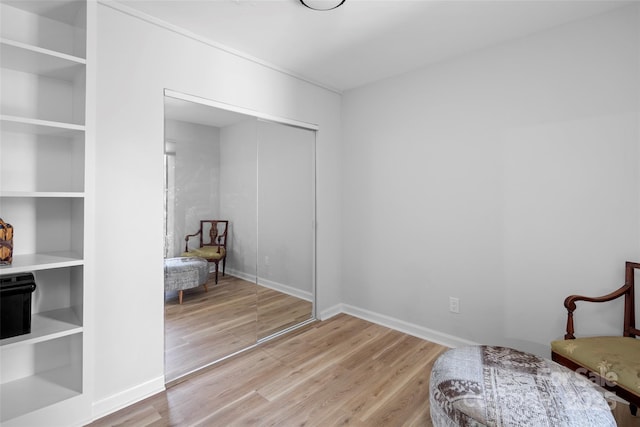 sitting room with built in shelves, wood finished floors, and baseboards