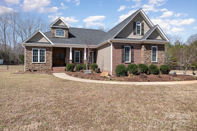 craftsman inspired home featuring brick siding, stone siding, a front lawn, and roof with shingles