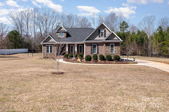 craftsman house featuring brick siding, stone siding, a front yard, and fence