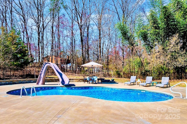 view of swimming pool featuring a patio area, a fenced in pool, a water slide, and fence