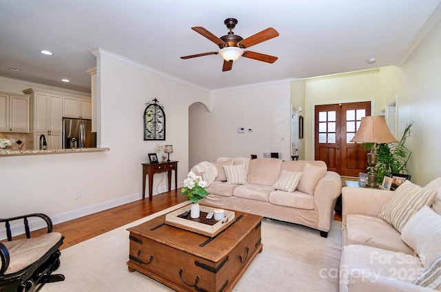 living room with ornamental molding, recessed lighting, arched walkways, light wood finished floors, and ceiling fan