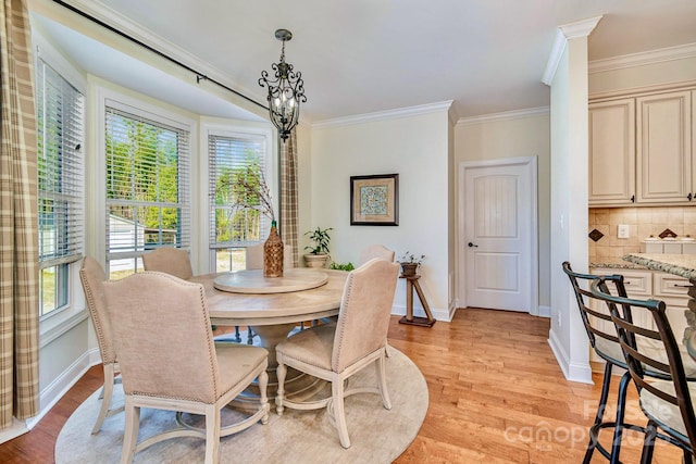 dining room with baseboards, an inviting chandelier, light wood-style flooring, and crown molding