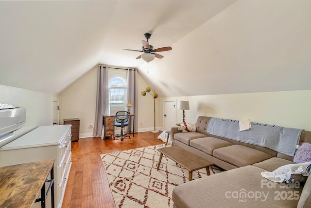 living area featuring baseboards, ceiling fan, vaulted ceiling, and light wood finished floors