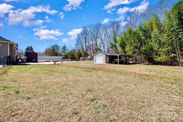 view of yard with a detached garage, an outbuilding, and fence