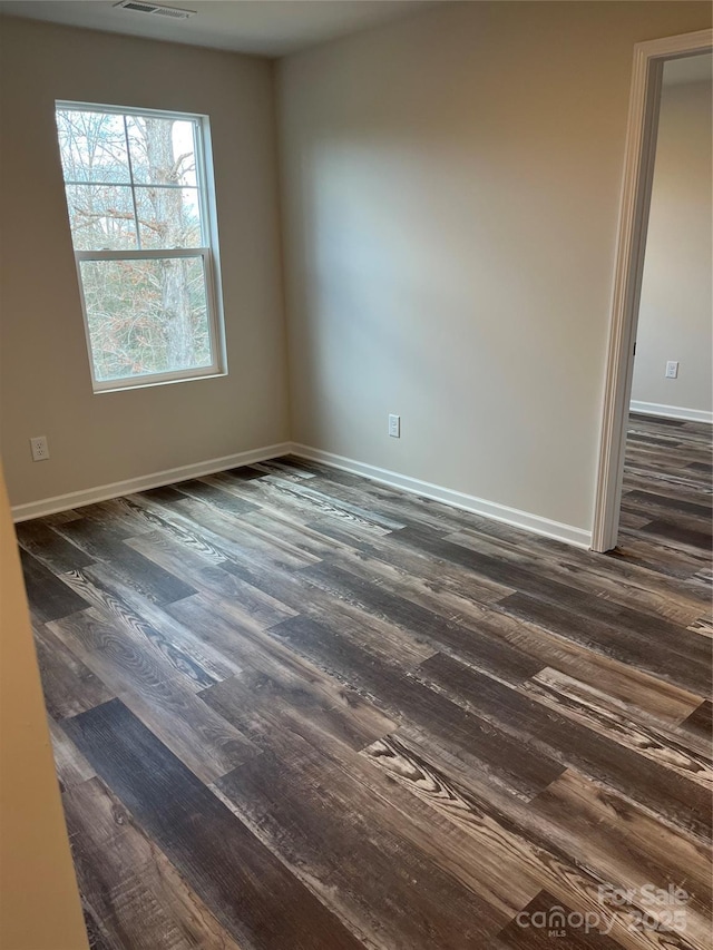 unfurnished room with visible vents, baseboards, and dark wood-type flooring