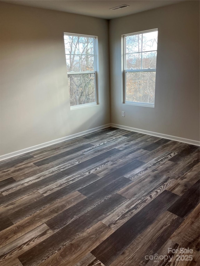 unfurnished room featuring visible vents, dark wood-type flooring, and baseboards