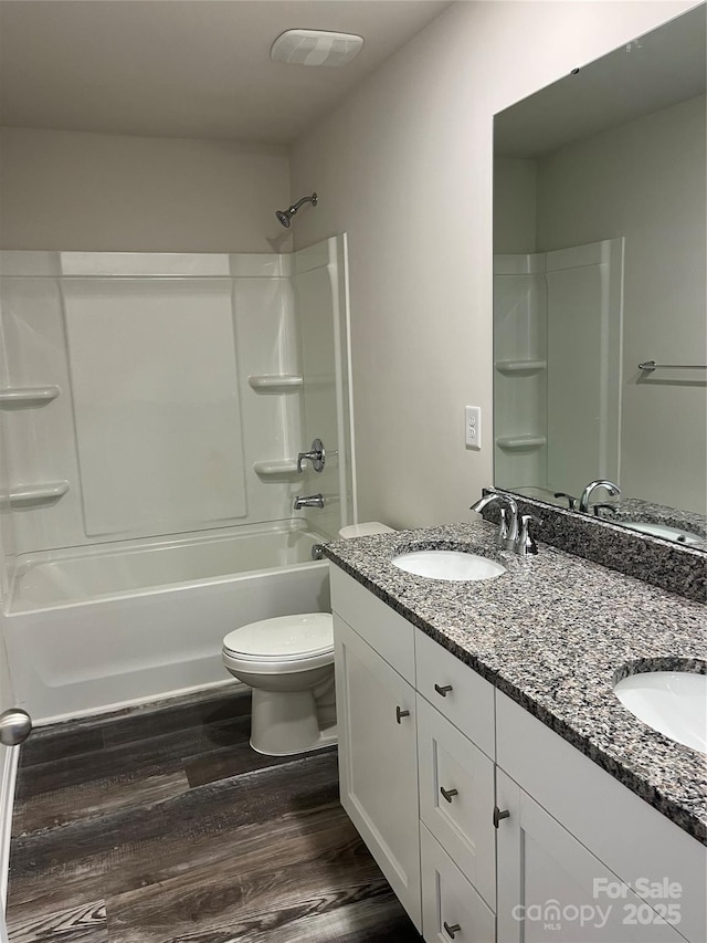 full bathroom featuring toilet, wood finished floors, and a sink