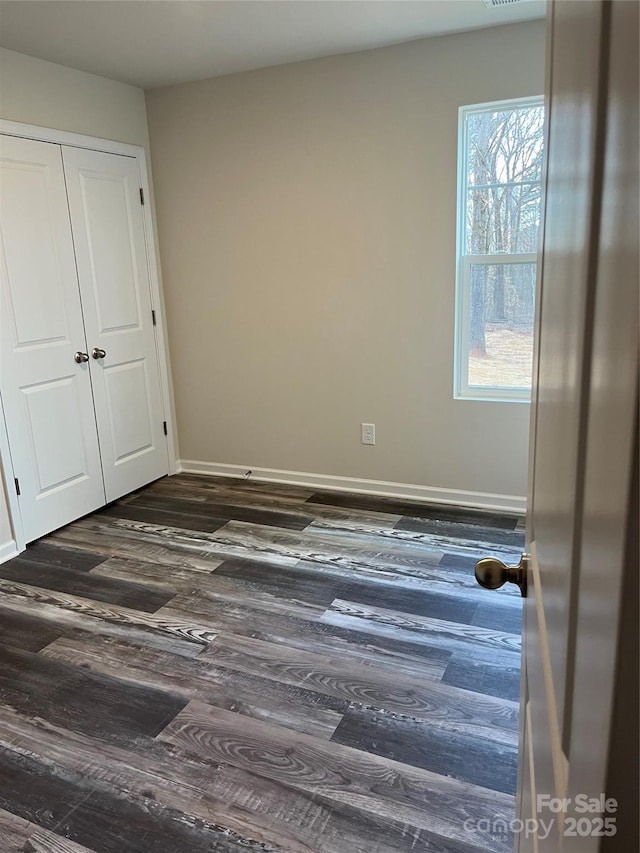 unfurnished bedroom featuring dark wood-type flooring and baseboards