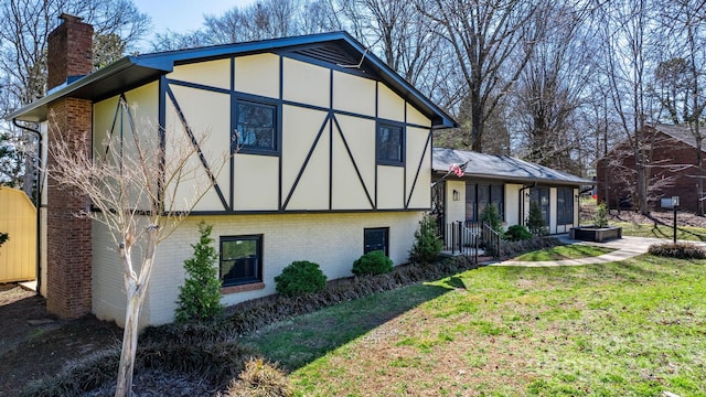 view of front of house featuring stucco siding, a front yard, brick siding, and a chimney